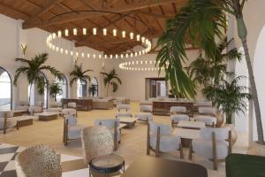 eine Lobby mit Tischen, Stühlen und Palmen in der Unterkunft Hotel Best Village Chipiona in Costa Ballena