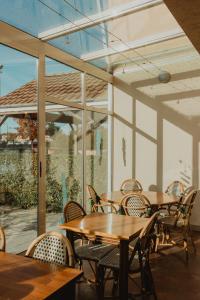 um pátio com mesas e cadeiras de madeira e janelas em Hôtel Akena Caudry Cambrai em Caudry