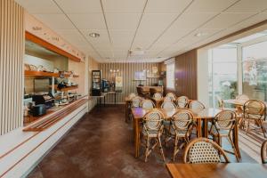 um restaurante com mesas e cadeiras e uma cozinha em Hôtel Akena Caudry Cambrai em Caudry