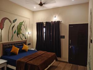 a bedroom with a bed with blue sheets and yellow pillows at Leaf Garden Retreat in Varkala