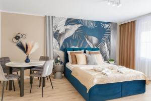 a bedroom with a blue bed and a table and chairs at Amber Premium Apartments in Bydgoszcz