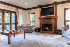 a living room with a fireplace and a tv at Muirs Reef Lodge Kinloch holiday home Lake Taupo in Kinloch