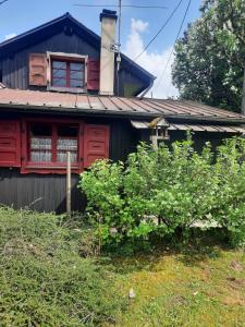 une maison avec une fenêtre rouge et des buissons devant dans l'établissement Chalet mayou, à Châtillon-sur-Cluses