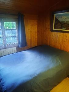 Ce lit se trouve dans une chambre en bois dotée d'une fenêtre. dans l'établissement Chalet mayou, à Châtillon-sur-Cluses