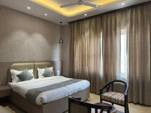 ein Schlafzimmer mit einem Bett und einem Stuhl und einem Fenster in der Unterkunft Duggar Haveli Hotel & Restaurant in Jammu + 16 Fotos