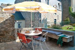 a table and chairs under an umbrella on a patio at Appartement d'exception - proche de la mer in Saint-Brieuc
