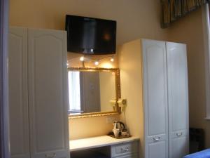 a bathroom with a mirror and a tv on the wall at Mermaid Suite Hotel in London