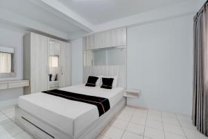 une chambre blanche avec un lit blanc avec des oreillers noirs dans l'établissement OYO 94838 Dahoma Tower, à Tjikuda Tiga