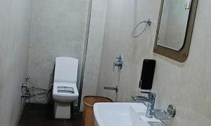 Un baño con inodoro, lavabo y espejo. en FabHotel Kalka Residency, en Nueva Delhi