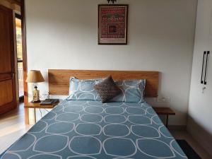 a bedroom with a blue bed with a wooden headboard at Tabula Raasa in Rānīkhet
