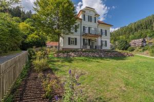 Teinach Suites - Villa Wilhelmshöhe في باد تايناخ-تسافلشتاين: بيت ابيض مع سياج وساحة