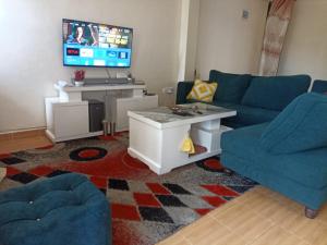 a living room with a blue couch and a tv at Jay homes in Kakamega