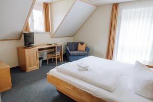 a bedroom with a bed and a desk and a television at Landgasthof Freiberger in Schnabelwaid