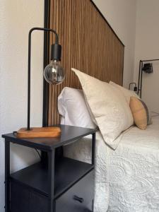 ein schwarzer Tisch mit einer Lampe neben einem Bett in der Unterkunft HostJimeno Otoño in La Garita + 6 Fotos