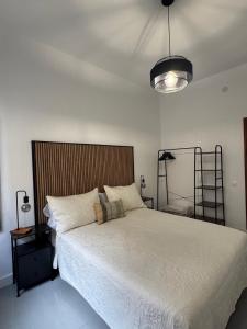 ein Schlafzimmer mit einem großen weißen Bett und einer Lampe in der Unterkunft HostJimeno Otoño in La Garita