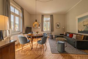 Teinach Suites - Villa Wilhelmshöhe في باد تايناخ-تسافلشتاين: غرفة معيشة مع أريكة وطاولة وكراسي +45 صورة