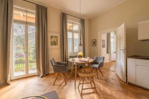 Teinach Suites - Villa Wilhelmshöhe في باد تايناخ-تسافلشتاين: مطبخ وغرفة طعام مع طاولة وكراسي