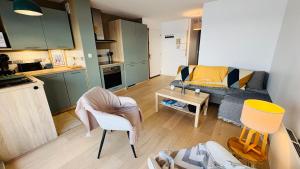 a living room with a couch and a table at Le Panorama, confortable appartement - accès direct à la plage in Bernières-sur-Mer +10 photos