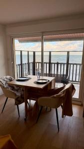 a dining room with a table and a view of the ocean at Le Panorama, confortable appartement - accès direct à la plage in Bernières-sur-Mer