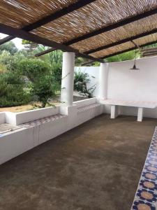 a patio with white benches and a wooden roof at Casa Moser in Stromboli +8 photos