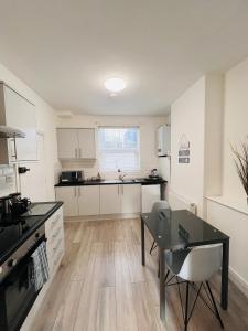 a kitchen with white cabinets and a dining table at Southside Street Apartments in Plymouth