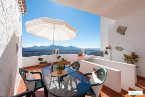 een tafel met stoelen en een parasol op een balkon bij Living Artenara - CAVE HOUSE & TERRACE Adults Only in Artenara