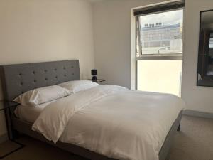 ein Schlafzimmer mit einem weißen Bett mit einem Fenster in der Unterkunft York City Centre 2 Bed Flat with Views - Steps from Christmas Market in York
