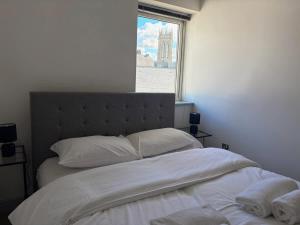 ein Schlafzimmer mit einem Bett mit weißen Laken und einem Fenster in der Unterkunft York City Centre 2 Bed Flat with Views - Steps from Christmas Market in York