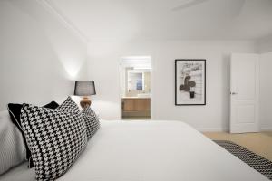 una camera bianca con letto bianco e cuscini di Urban Haven Central Wagga a Wagga Wagga