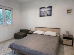 a bedroom with a bed and a chair at Apartments Giran in Lokva Rogoznica
