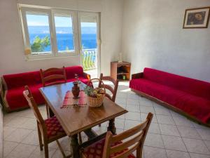 a living room with a table and a red couch at Apartments Giran in Lokva Rogoznica