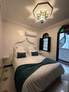 a bedroom with a large bed and a chandelier at Ryad Lalla khadija in Marrakech