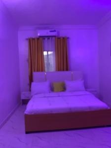 a purple bedroom with a bed with a window at Vivi apartment hotel and suite in Sapele