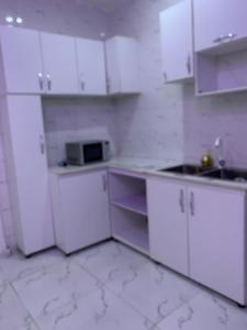 a white kitchen with white cabinets and a microwave at Vivi apartment hotel and suite in Sapele