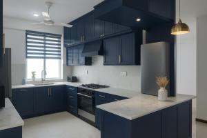 a kitchen with navy blue cabinets and a refrigerator at Deluxe 4BR Penthouse By Unique Towers in Colombo