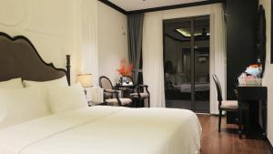 ein Schlafzimmer mit einem weißen Bett und einem Tisch und Stühlen in der Unterkunft Royal Hotel - Trinh Van Bo, Nam Tu Liem in Văn Trì