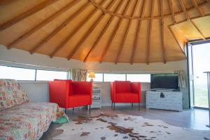 a bedroom with a bed and two red chairs at MoinhoPontoCom in Rio Maior