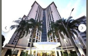 a tall building with palm trees in front of it at Flat próximo ao Aeroporto Congonhas Piscina, Academia e Restaurante in São Paulo