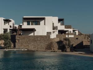 a building next to a stone wall and water at Armacaas Mykonos Hotel in Super Paradise Beach