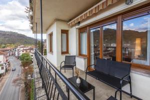 a balcony with two chairs and a view of a street at Bizi Baztan Apartamento Aguirre in Elizondo