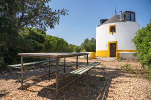 a picnic table and a bench in front of a lighthouse at Moinho da Senta in Rio Maior