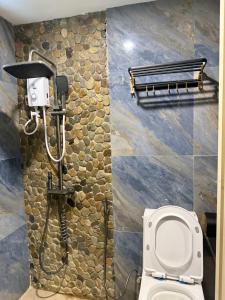 een badkamer met een toilet en een stenen muur bij R&C Transient House in El Nido +6 foto's