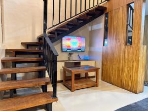 een woonkamer met een trap en een tv bij R&C Transient House in El Nido