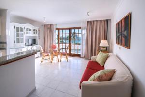 Una sala de estar con un sofá rojo y una cocina. en Playa Delphin 303, en Puerto Naos