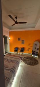 a bedroom with a bed and two chairs and a ceiling fan at SAMANI Homestay in Rishīkesh +19 photos