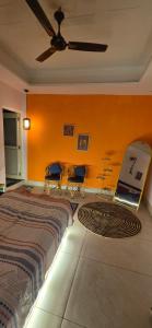 a bedroom with a bed and chairs and a ceiling fan at SAMANI Homestay in Rishīkesh