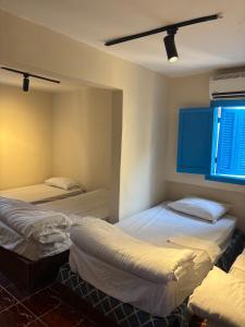 a room with three beds and a window at Colour Holidays in Cairo