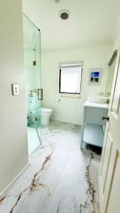 um banheiro branco com uma pia e um espelho em Beach Apartment em Papamoa