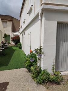 滨海布雷蒂尼奥勒Maison de bourg cosy et fonctionnelle proche mer的一栋白色建筑，旁边是院子，院子里种满了鲜花。