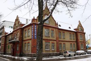 a large brick building with cars parked in front of it at Hostel Lõuna in Pärnu